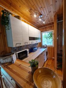 a kitchen with white cabinets and a wooden ceiling at Domek nad jeziorem Anastazewo in Anastazewo