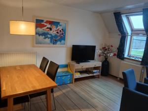 un soggiorno con tavolo da pranzo e televisore di Centrum 26 a Brouwershaven