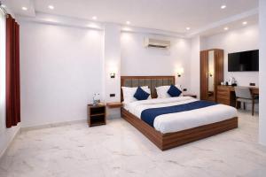 a bedroom with a bed and a desk and a television at Hotel Hare Krishna & Banquet, Vrindavan in Vrindāvan +14 photos