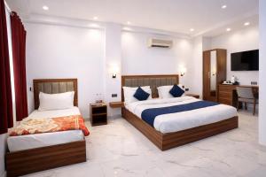 a hotel room with two beds and a desk at Hotel Hare Krishna & Banquet, Vrindavan in Vrindāvan