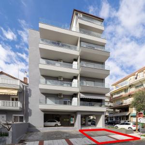 a tall white building with a red rug in front of it at Anatoli Urban Apartment with private parking in Xanthi