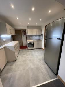 a kitchen with white cabinets and a stainless steel refrigerator at Le Chalet in Les Deux Alpes