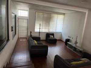 a living room with two couches and a cross on the window at La Casa de Ikal Zacatlán in Zacatlán