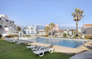 a swimming pool with white lounge chairs next to a building at RJ Summer in Sagres