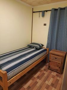 a bed in a room with a blue curtain at Cabañas Gasparín Sur in Río Bueno