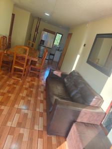 a living room with a leather couch and a table at Cabañas Gasparín Sur in Río Bueno