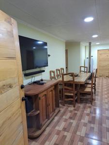 a dining room with a table and a large screen television at Cabañas Gasparín Sur in Río Bueno