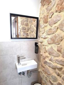 a bathroom with a sink and a stone wall at Casa Trilles in Azuébar