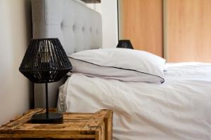 a bed with white sheets and a lamp on a table at Pause Pedal Pyrénées in Capvern