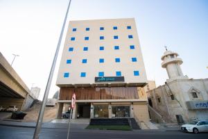 a tall building with a lighthouse in front of it at فندق اسكان وافر in An Naqāʼ