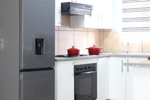 a kitchen with white cabinets and red pots on the stove at Stonewall Luxury Apartment in Northriding