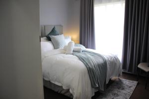 a bedroom with a bed with white sheets and a window at Stonewall Luxury Apartment in Northriding