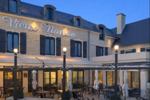 a hotel with tables and chairs in front of it at Logis Hôtel-Restaurant Au Vieux Morvan, au cœur de la Bourgogne, Piscine & Spa, Hôtel Climatisé in Château-Chinon