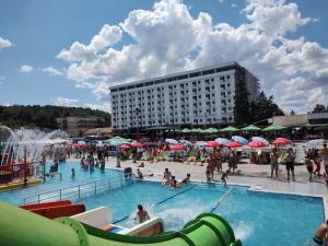 a group of people in a swimming pool with a building at Zeus Apartman in Jagodina