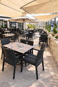 an outdoor patio with tables and chairs and umbrellas at Logis Hôtel-Restaurant Au Vieux Morvan, au cœur de la Bourgogne, Piscine & Spa, Hôtel Climatisé in Château-Chinon