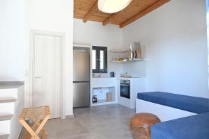 a kitchen with white walls and a blue couch in a room at Alkyoni Celeste Kythnos in Kithnos
