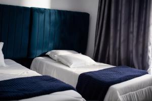 two beds in a hotel room with blue curtains at Muka Staytel in Ndola +15 photos