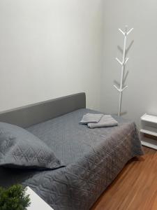 a bed in a white room with a gray comforter at Apê do Viajante in Vila Velha