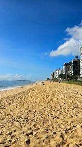a beach with footprints in the sand and buildings at Apê do Viajante in Vila Velha