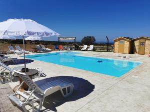 a swimming pool with chairs and an umbrella at A Valata di Donnafugata in Ragusa
