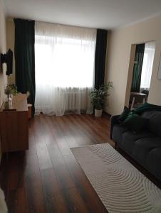 a living room with a couch and a large window at Апартаменти GREEN центр вулиця Руська in Ternopil
