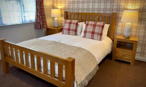 a bedroom with a wooden bed with pillows and two lamps at Sibton White Horse Inn in Saxmundham