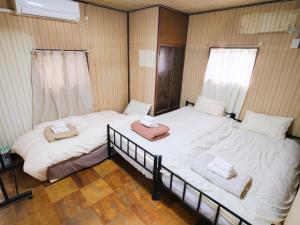 two beds in a room with white sheets and towels at Hikari-Private House in Tokyo