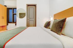a bedroom with a large white bed with a mirror at Hotel O Crowninn in Faridabad