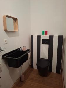 a bathroom with a black toilet and a sink at La Vie en Rose in Ensival