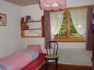 ein Schlafzimmer mit einem Bett, einem Stuhl und einem Fenster in der Unterkunft La Drossa in Lenzerheide