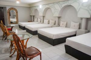 ein Zimmer mit drei Betten und einem Tisch und einem Spiegel in der Unterkunft Hotel Santander Veracruz in Veracruz