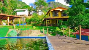 a house with a pond in front of a house at Sitio Ziriguidum in Nova Friburgo