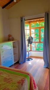a bedroom with a bed and a dresser and a window at Sitio Ziriguidum in Nova Friburgo