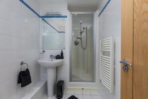 a white bathroom with a shower and a sink at The Midnight Parlour in Leeds