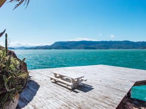 a bench sitting on top of a wooden dock near the water at Vilatoro Guest House in Ilhabela