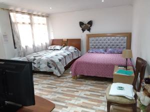 a bedroom with two beds and a flat screen tv at Casa Turistica Andy in Cali