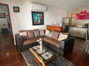 a living room with a brown couch and a kitchen at Coras Place Bacalar Lagoon front in Bacalar