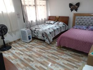 a bedroom with two beds and a television on a wooden floor at Casa Turistica Andy in Cali