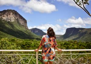 eine Frau, die auf einem Geländer steht und auf die Berge blickt in der Unterkunft Pousada do Capão Chapada Diamantina in Vale do Capao
