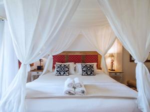 a bedroom with a white bed with towels on it at Vilatoro Guest House in Ilhabela