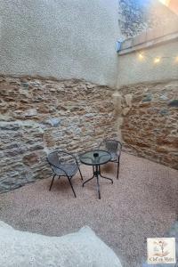 two chairs and a table in front of a stone wall at Le Petit Cocon Cozy studio proche de Lyon in Couzon-au-Mont-dʼOr