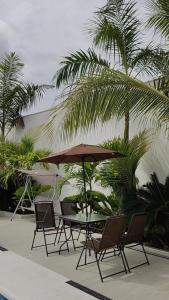 a table and chairs with an umbrella and palm trees at Villa Luna Hotel-Eventos in Carmen de Apicalá