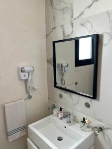 a white bathroom with a sink and a mirror at Comfortable and Fresh Apartment in Tunis