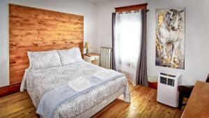 a bedroom with a bed and a wooden wall at Auberge Ayer's Cliff in Ayers Cliff