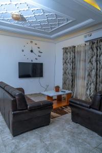 a living room with two leather couches and a tv at MICASO Guest House in Limbe