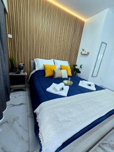 a bedroom with a large blue bed with yellow pillows at Marble Coast Studio Apartment in Larnaca