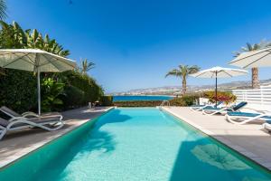 a swimming pool with chairs and umbrellas at Beachfront Villa Mare with Jaccuzi and Infinity Pool in Kissonerga +89 photos