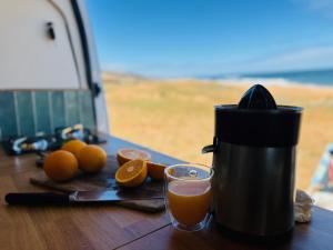 a coffee maker and a glass of orange juice on a table at Van aménagé tout confort in Tamaris