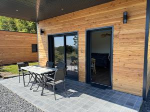 a patio with a table and chairs in front of a house at Le Buchon Lodge in Montcornet