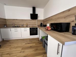 a kitchen with white cabinets and a wooden wall at L'abeille sous les étoiles in Saint-Michel-lʼObservatoire
